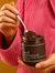 Person holding a jar of 'well seasoned' pistachio & dark chocolate butter with a spoon.