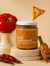 Jar of 'well seasoned' spice mix with a tomato, pepper, and tortilla chip on a beige background