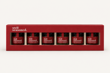 Box of 'well seasoned' mini oil bottles on a white background