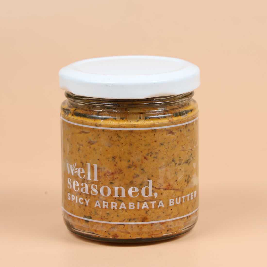 Jar of 'well seasoned' spice mix with a tomato, pepper, and tortilla chip on a beige background